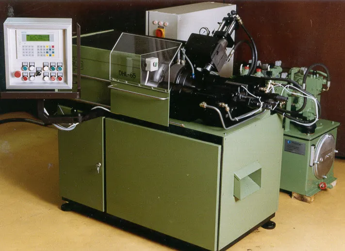 Archivfoto der frühen Harlo-Maschine DHL-65: grüner Maschinenkörper, links das stehende Bedienpult, rechts das Hydraulikaggregat
