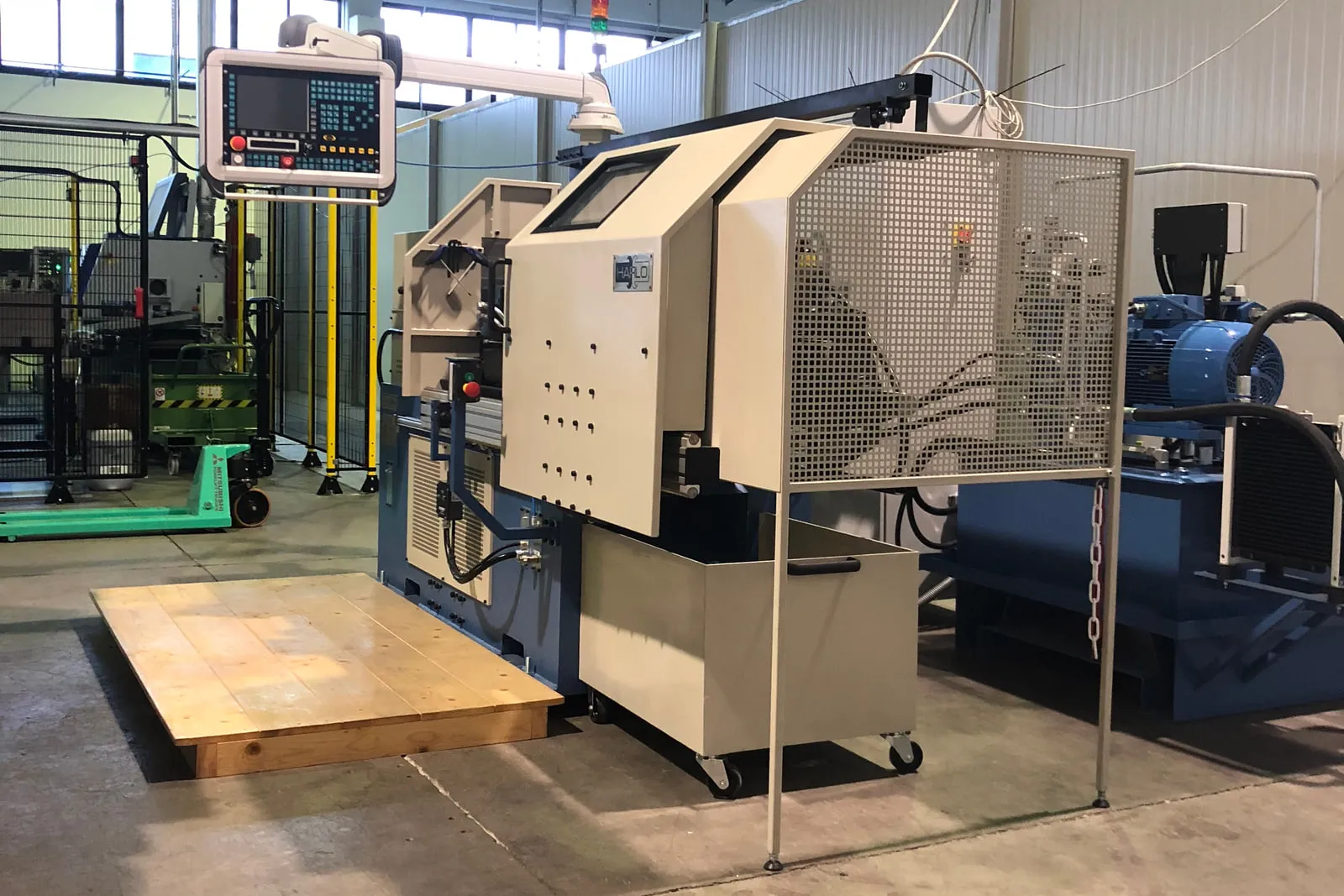 Friction welding machine in the production hall, with a hydraulic power unit beside it