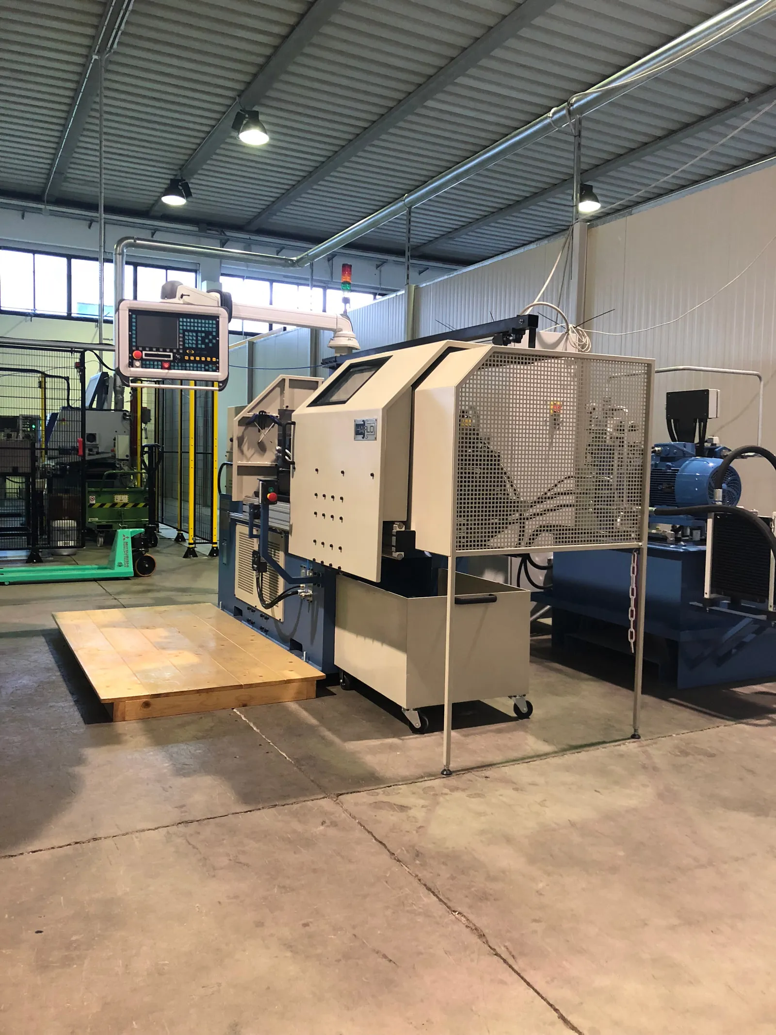Friction welding machine with safety fence in the production hall, a pallet beside it